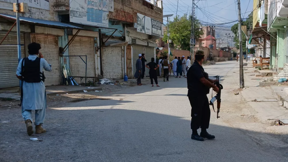 In this photo taken with a smartphone, police officers secure a road leading to the site of a powerful bomb at a mosque in Kohat, Pakistan, Friday, Sept. 18, 2026. (AP Photo/B.S. Gillani)