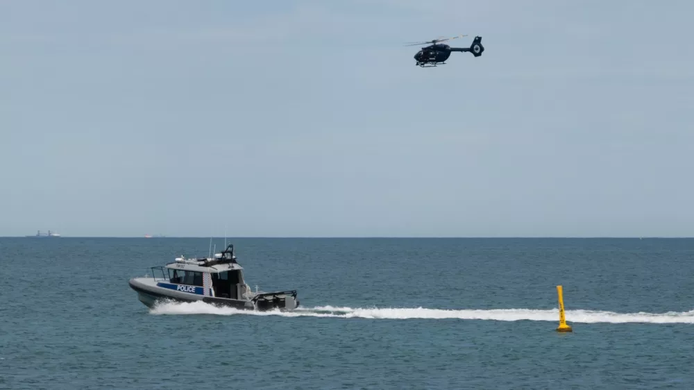 A police boat and and helicopter patrol the area at Sorrento Beach, in Perth, Australia, Friday, Sept. 18, 2026, after a suspected fatal shark attack. (Andrew O'Connor/Australian Broadcasting Corp via AP)