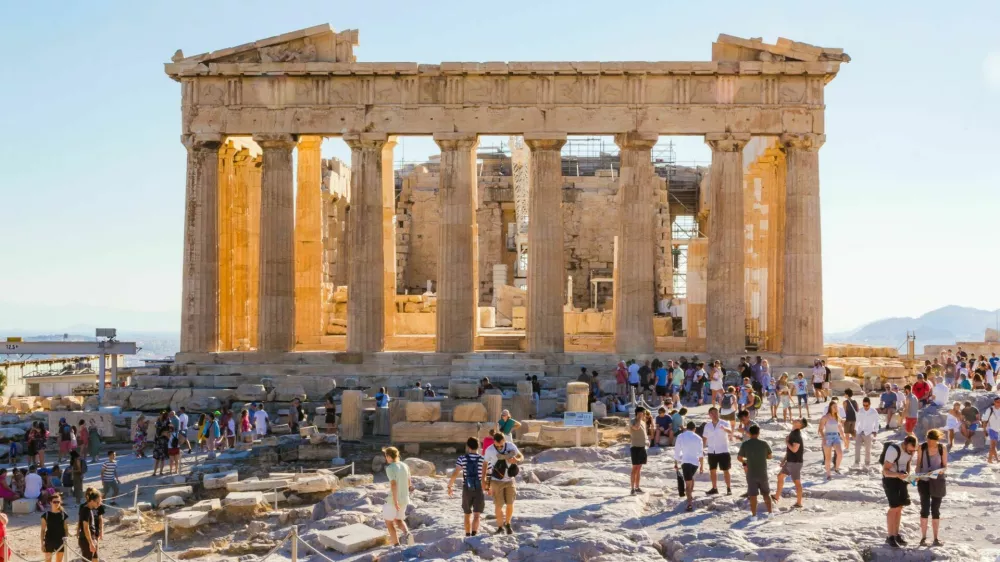 Crowds of tourists visit everyday the Parthenon in the Acropolis in Athens, Greece. At sunset heat decreases and shadows are long.