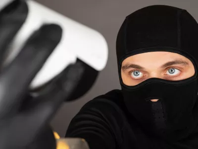 Picture of thief wearing black face mask is trying to turn off a surveillance camera