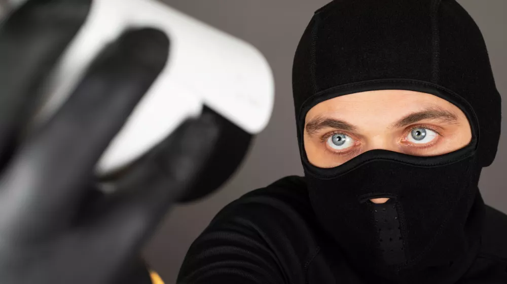 Picture of thief wearing black face mask is trying to turn off a surveillance camera