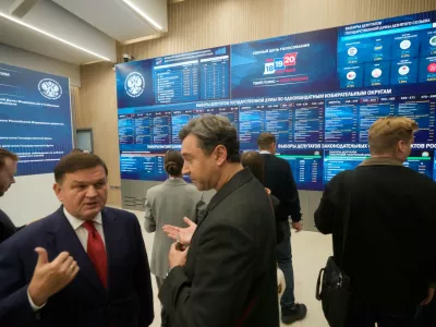 People stand next to video screens sowing preliminary voting results for Russian parliamentary elections at Russia's Central Election Committee headquarters, in Moscow, Russia, Monday, Sept. 21, 2026. (AP Photo/Pavel Bednyakov)