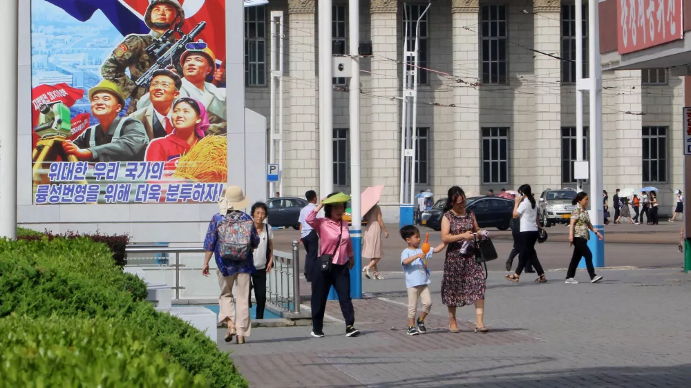 People walk in the street of the Central District in Pyongyang, North Korea, Monday, June 22, 2026. The poster reads, "Let us make strenuous efforts for the prosperity of our great state!" (AP Photo/Jon Chol Jin)
