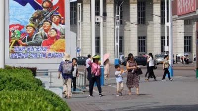 People walk in the street of the Central District in Pyongyang, North Korea, Monday, June 22, 2026. The poster reads, "Let us make strenuous efforts for the prosperity of our great state!" (AP Photo/Jon Chol Jin)