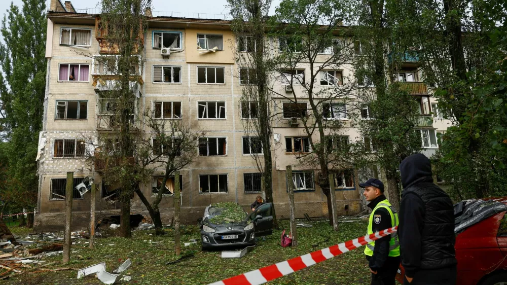 A police officer and residents stand in front of an apartment building which was hit by a Russian drone strike, amid Russia's attack on Ukraine, in Kyiv, Ukraine September 22, 2026. REUTERS/Valentyn Ogirenko