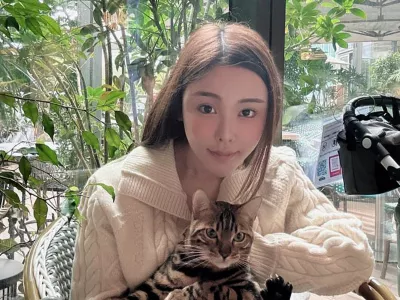 Abby Choi holds a cat and poses, Feb. 11, 2023, in Hong Kong. (AP Photo)