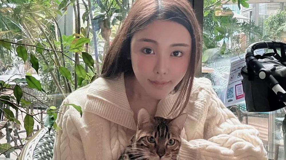 Abby Choi holds a cat and poses, Feb. 11, 2023, in Hong Kong. (AP Photo)
