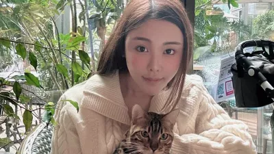 Abby Choi holds a cat and poses, Feb. 11, 2023, in Hong Kong. (AP Photo)