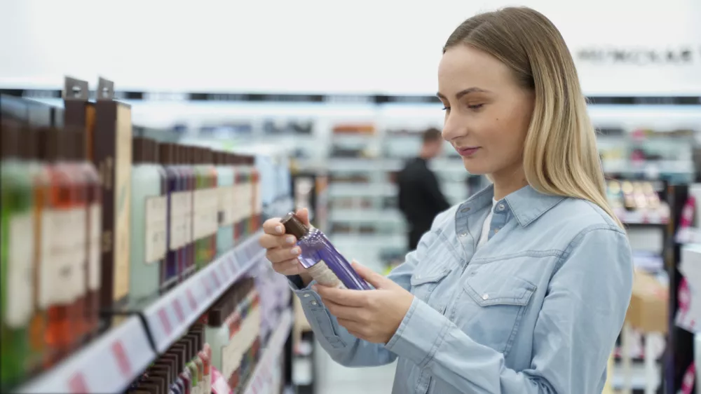 Shopping - young woman holding bottle of shampoo in supermarket. / Foto: Viktoria Korobova Getty Images