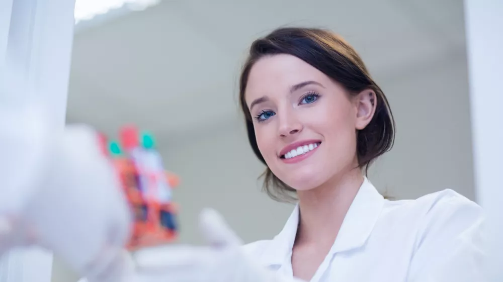 Young female biologist smiling at the camera in hospital / Foto: Wavebreakmedia Getty Images