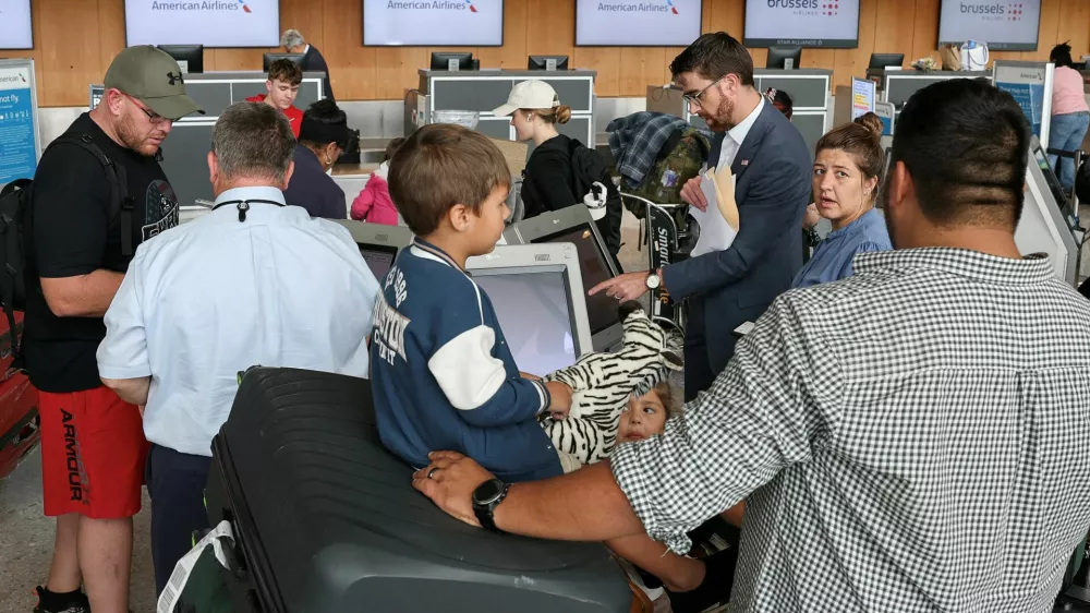 FILE PHOTO: A U.S. State Department official helps people from the first group of white South Africans granted refugee status for being deemed victims of racial discrimination under U.S. President Trump's Refugee plan, check in for a connecting flight, at Dulles International Airport, in Dulles, Virginia, U.S., May 12, 2025. REUTERS/Jonathan Ernst/File Photo