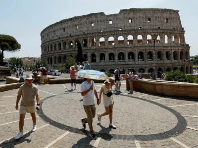 FILE PHOTO: A person holds an umbrella as people walk near the Colosseum during a heatwave across Italy, as temperatures are expected to rise further in the coming days, in Rome, Italy August 3, 2026. REUTERS/Remo Casilli/File Photo