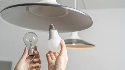 Energy saving idea: Asian people replace fluorescent light bulbs (CFL) with new LED bulbs. Female hands screw in an energy-saving LED light bulb. / Foto: Jittawit.21 Getty Images