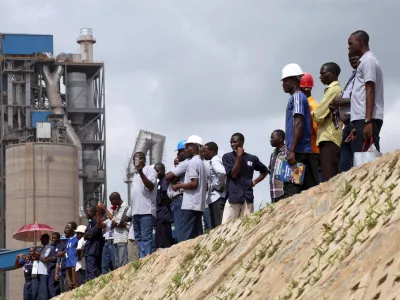 FILE PHOTO: Workers stand on the pavement during a commissioning ceremony at Dangote cement factory in Obajana in Nigeria's central state of Kogi June 11, 2012. Nigerian billionaire Aliko Dangote commissioned an expansion of his Obajana cement plant on Monday that raised its capacity to 10.25 million tonnes a year, creating what he called a "powerhouse of cement" in Africa and the world. REUTERS/Akintunde Akinleye (NIGERIA - Tags: POLITICS BUSINESS CONSTRUCTION EMPLOYMENT)/File Photo