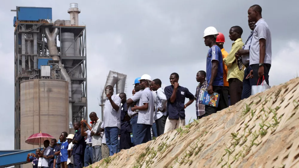 FILE PHOTO: Workers stand on the pavement during a commissioning ceremony at Dangote cement factory in Obajana in Nigeria's central state of Kogi June 11, 2012. Nigerian billionaire Aliko Dangote commissioned an expansion of his Obajana cement plant on Monday that raised its capacity to 10.25 million tonnes a year, creating what he called a "powerhouse of cement" in Africa and the world. REUTERS/Akintunde Akinleye (NIGERIA - Tags: POLITICS BUSINESS CONSTRUCTION EMPLOYMENT)/File Photo