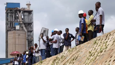 FILE PHOTO: Workers stand on the pavement during a commissioning ceremony at Dangote cement factory in Obajana in Nigeria's central state of Kogi June 11, 2012. Nigerian billionaire Aliko Dangote commissioned an expansion of his Obajana cement plant on Monday that raised its capacity to 10.25 million tonnes a year, creating what he called a "powerhouse of cement" in Africa and the world. REUTERS/Akintunde Akinleye (NIGERIA - Tags: POLITICS BUSINESS CONSTRUCTION EMPLOYMENT)/File Photo