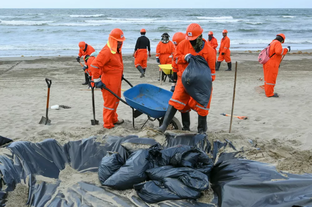 A crew of workers from Constructora y Comercializadora Maya, subcontracted by state oil company Pemex to clean black tar slicks from beaches, work along the shoreline amid local fears that more crude oil could wash ashore nearly a month after the first signs of contamination were detected in the states of Veracruz and Tabasco, in Coatzacoalcos, Mexico, March 24, 2026. REUTERS/Angel Hernandez