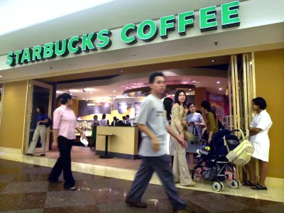 Shoppers walk past a Starbucks coffee shop at a mall in Jakarta, Indonesia, Wednesday, May 22, 2002. The Seattle-based coffee chain giant opened it first store in Indonesia last week. (AP Photo/Achmad Ibrahim)