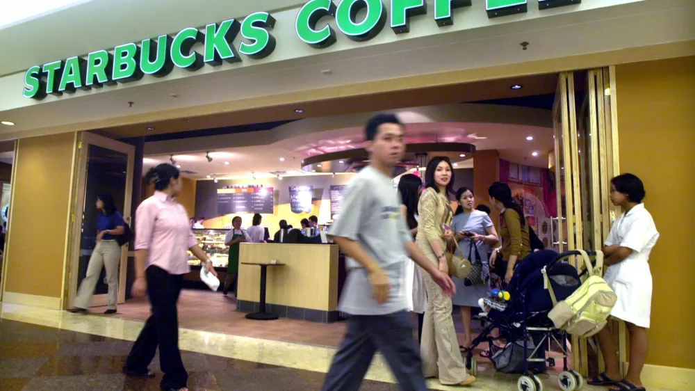 Shoppers walk past a Starbucks coffee shop at a mall in Jakarta, Indonesia, Wednesday, May 22, 2002. The Seattle-based coffee chain giant opened it first store in Indonesia last week. (AP Photo/Achmad Ibrahim)