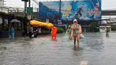 In this photo taken with a smartphone, people wade through floodwaters after heavy rain in Bangkok, Thailand Saturday, Sept. 26, 2026. (AP Photo/Adam Schreck)