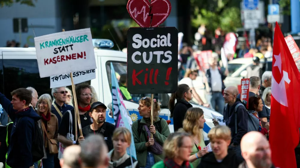 People hold signs as they attend a protest of the German Trade Union Confederation (DGB) against social cuts, in Berlin, Germany, September 26, 2026. REUTERS/Maryam Majd