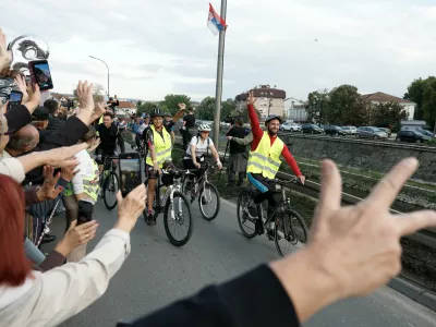 People welcome a group of university students at the end of their cycling tour of the Balkan country ahead of an early election next month challenging populist President Aleksandar Vucic, in Kragujevac, Serbia, Saturday, Sept. 26, 2026. (AP Photo/Marko Drobnjakovic)
