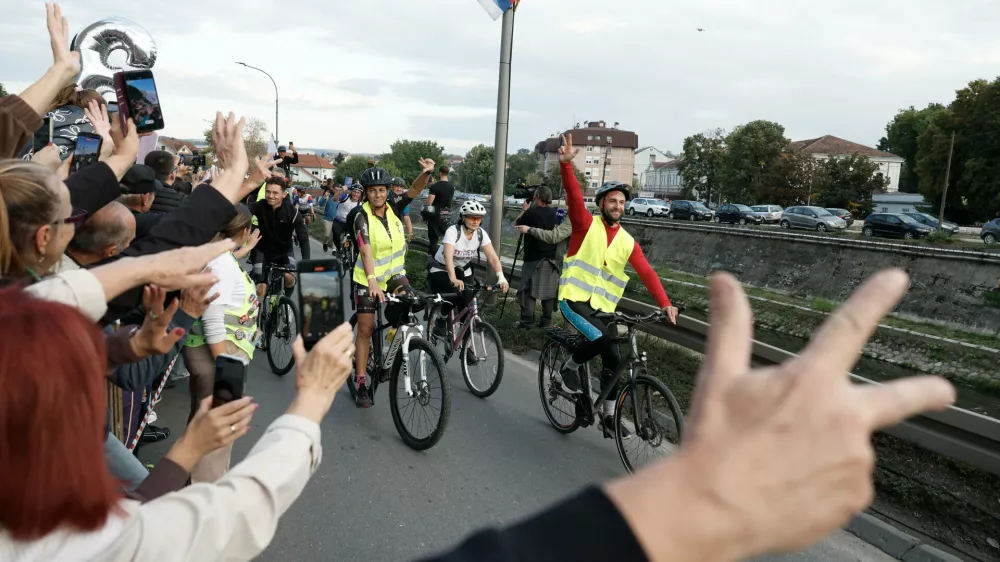 People welcome a group of university students at the end of their cycling tour of the Balkan country ahead of an early election next month challenging populist President Aleksandar Vucic, in Kragujevac, Serbia, Saturday, Sept. 26, 2026. (AP Photo/Marko Drobnjakovic)