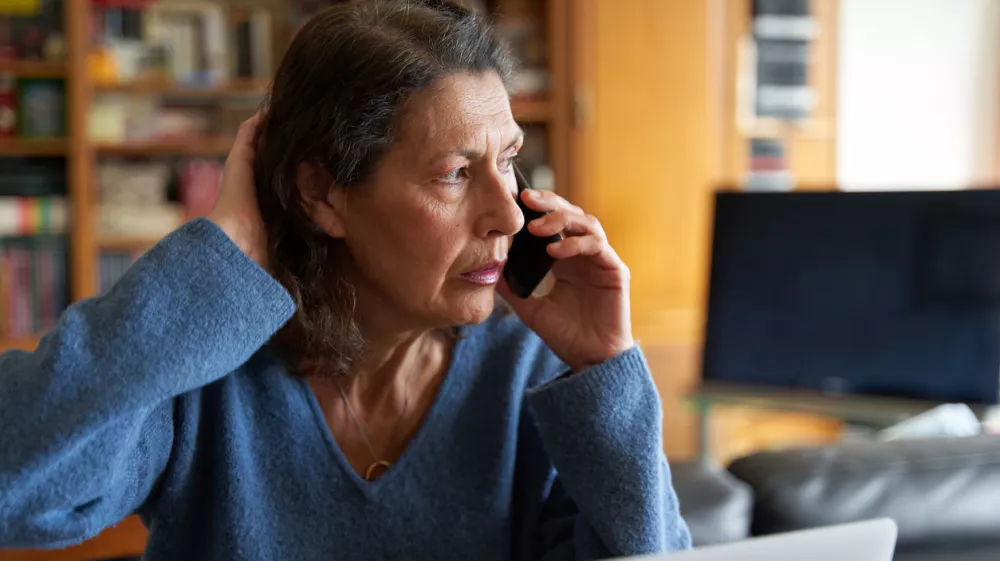 Stressed senior businesswoman on the phone while working on laptop