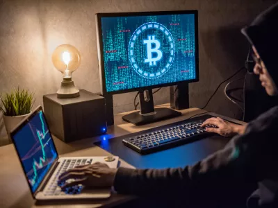 Hacker man using laptop and computer with Bitcoin green binary graphic and cryptocurrency candlestick graph price on monitor screen. Cyber crime digital currency laundering concept