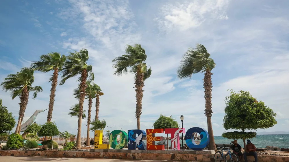 People sit near a logo in Loreto, as Hurricane Polo approaches Baja California Sur, Mexico, September 28, 2026. REUTERS/Raquel Cunha