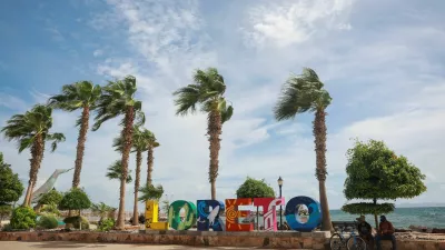 People sit near a logo in Loreto, as Hurricane Polo approaches Baja California Sur, Mexico, September 28, 2026. REUTERS/Raquel Cunha
