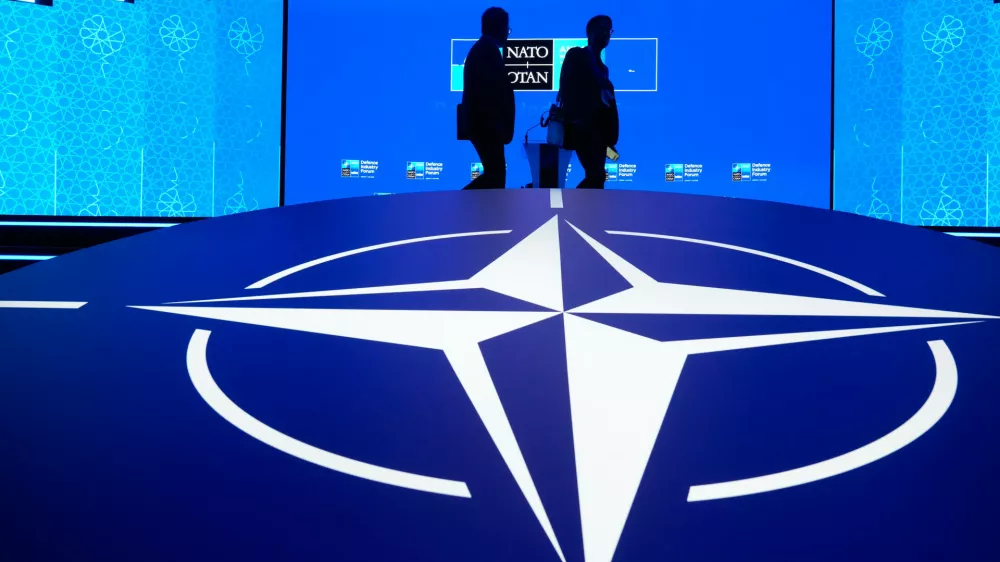 Two men walk past the NATO logo during the NATO Defense Industry Forum at the NATO summit in Ankara, Turkey, Tuesday, July 7, 2026. (AP Photo/Hussein Malla)