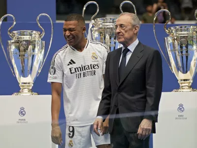 Kylian Mbappe, of France, smiles next to Real Madrid President Florentino Perez while being presented to fans as a new Real Madrid player at the Santiago Bernabeu stadium in Madrid, Tuesday, July 16, 2024. (AP Photo/Andrea Comas)