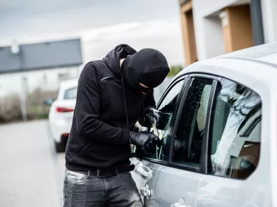 Car thief trying to break into a car with a screwdriver. Car thief, car theft. / Foto: Djedzura