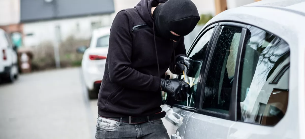 Car thief trying to break into a car with a screwdriver. Car thief, car theft. / Foto: Djedzura