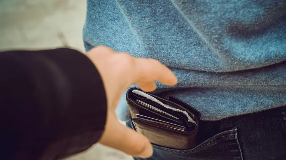one hand reaches for a purse in the back pocket
