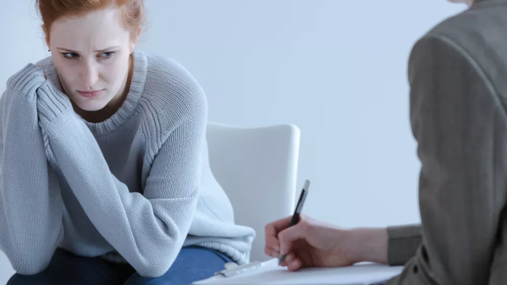 Sad young woman with eating disorders during meeting with psychotherapist