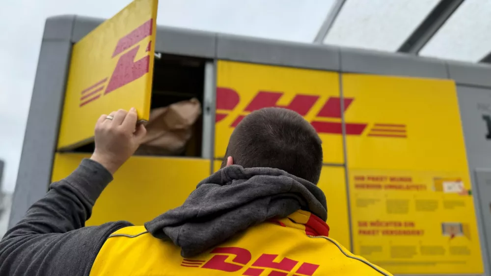 FILED - 02 December 2024, North Rhine-Westphalia, Duesseldorf: A DHL parcel carrier stands at a Packstation to fill it with parcels. Photo: Wolf von Dewitz/dpa-Zentralbild/dpa