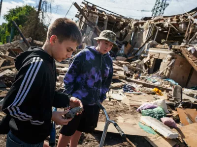 A boy looks at fragment of a rocket in front of a residential house destroyed in a Russian missile strike on Vyshhorod, Kyiv region, Ukraine, Wednesday, Sept. 30, 2026. (AP Photo/Evgeniy Maloletka)