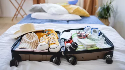 An open suitcase packed for holiday on bed at home, coronavirus concept.
