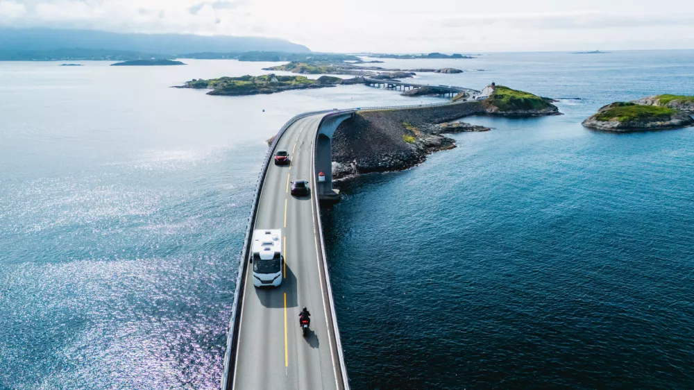 Travelers navigate the Atlantic Ocean Road, showcasing scenic landscapes and beautiful water views. Camper on the road in Norway