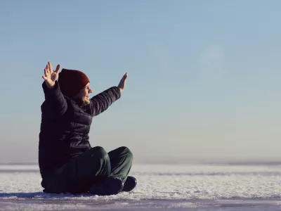 a young man sits in the winter on the ice of snow and looks at the sun. space for text