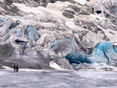 FILE &mdash; Team members of ETH (Swiss Federal Institute of Technology) glaciologist and head of the Swiss measurement network 'Glamos', Matthias Huss, arrive at the Rhone Glacier partially covered near Goms, Switzerland, June 16, 2023. (AP Photo/Matthias Schrader, File) / Foto: Matthias Schrader
