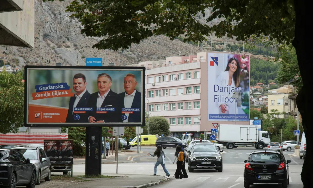 People walk past a campaign billboard featuring Democratic Front (Demokratska fronta) members Arman Zalihic, Zeljko Komsic and Zoran Mikulic, with a billboard featuring Darijana Filipovic, a candidate of the Croat Democratic Union of Bosnia and Herzegovina (HDZ BiH) for the Croat member of the Presidency of Bosnia and Herzegovina, in the background, ahead of the 2026 general election, in Mostar, Bosnia and Herzegovina, September 25, 2026. REUTERS/Amel Emric