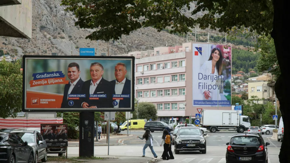 People walk past a campaign billboard featuring Democratic Front (Demokratska fronta) members Arman Zalihic, Zeljko Komsic and Zoran Mikulic, with a billboard featuring Darijana Filipovic, a candidate of the Croat Democratic Union of Bosnia and Herzegovina (HDZ BiH) for the Croat member of the Presidency of Bosnia and Herzegovina, in the background, ahead of the 2026 general election, in Mostar, Bosnia and Herzegovina, September 25, 2026. REUTERS/Amel Emric