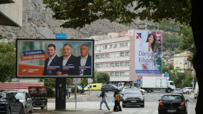 People walk past a campaign billboard featuring Democratic Front (Demokratska fronta) members Arman Zalihic, Zeljko Komsic and Zoran Mikulic, with a billboard featuring Darijana Filipovic, a candidate of the Croat Democratic Union of Bosnia and Herzegovina (HDZ BiH) for the Croat member of the Presidency of Bosnia and Herzegovina, in the background, ahead of the 2026 general election, in Mostar, Bosnia and Herzegovina, September 25, 2026. REUTERS/Amel Emric