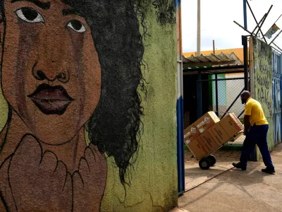 A worker transports boxes containing electronic voting machines into a public school where polling stations will be set up ahead of the general elections in Brasilia, Brazil, Friday, Oct. 2, 2026. (AP Photo/Eraldo Peres)