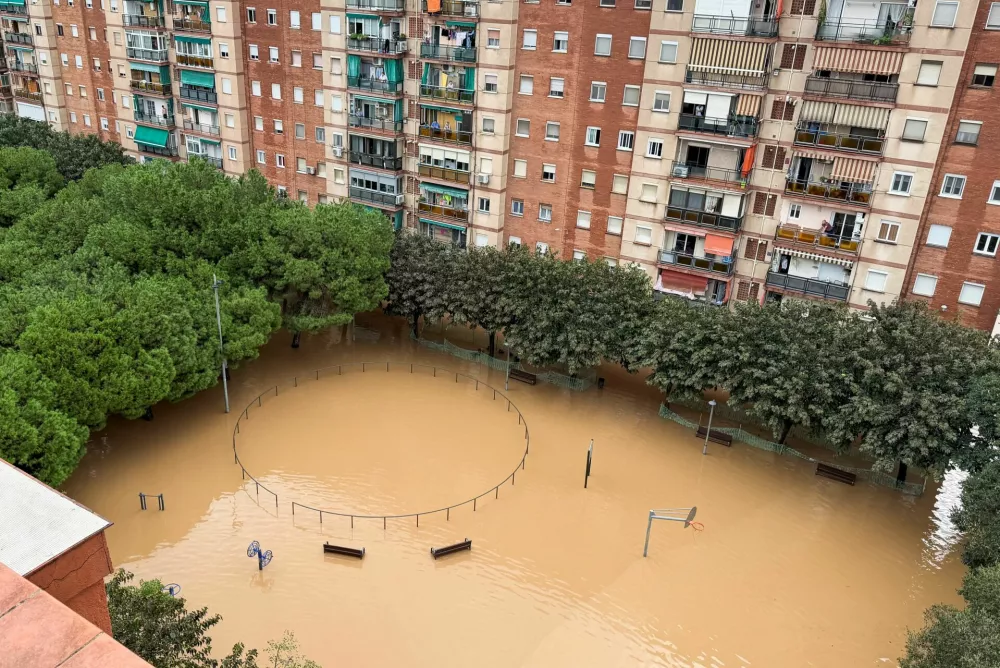 People look out at the flooded playground from their balconies following heavy rain, after Spain's meteorological agency AEMET issued a red alert for Catalonia, in Sant Adria de Besos, on the outskirts of Barcelona, Spain, October 4, 2026. REUTERS/Horaci Garcia