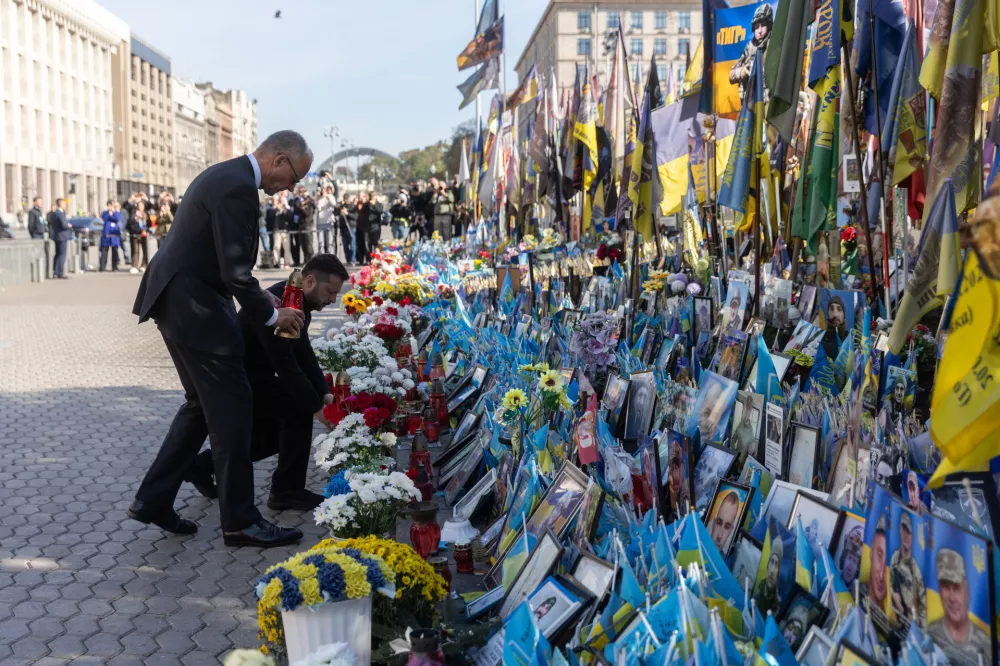 In this photo provided by the Press Service of The President of Ukraine, German Chancellor Friedrich Merz, left, and Ukrainian President Volodymyr Zelenskyy pay tributes at the memorial of fallen Ukrainian soldiers at the Independence square in Kyiv, Ukraine, Sunday, Oct. 4, 2026. (Press Service of The President of Ukraine via AP)