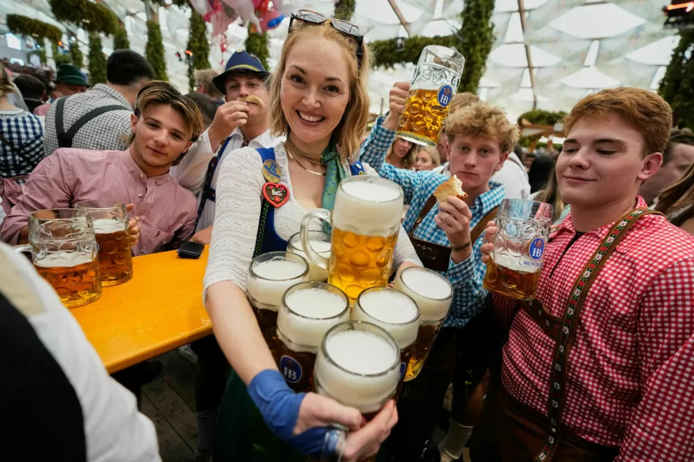 A waitress carries beer mugs after the opening of the 191st Oktoberfest beer festival in Munich, Germany, Saturday, Sept.19, 2026. (AP Photo/Matthias Schrader)